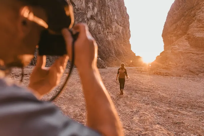 a man taking a picture of a woman in the desert