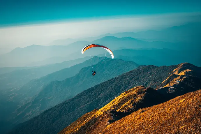 person in parachute over mountains during daytime